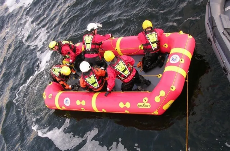 An Inflatable Rescue Raft in the Water with Six Members of Search and Rescue